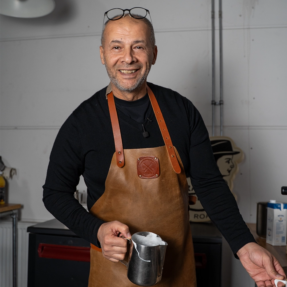 Dos van Lorando & Morini houdt een melkkan vast voor het opschuimen van melk voor koffie.