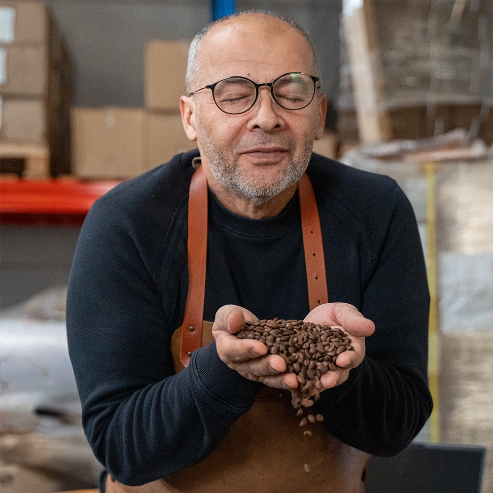 Koffiebrander ruikt aan een handvol vers gebrande koffiebonen in een branderij.
